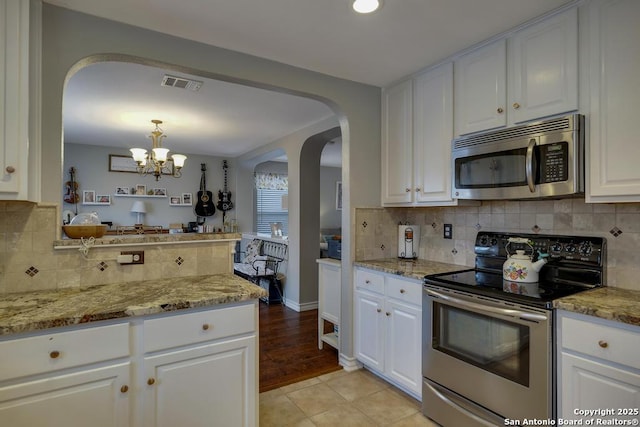 kitchen featuring light stone countertops, pendant lighting, stainless steel appliances, white cabinetry, and light tile patterned flooring