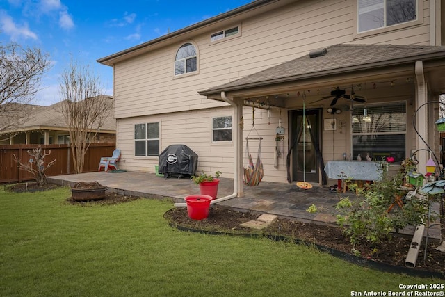 back of property with ceiling fan, a fire pit, a yard, and a patio area