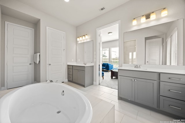 bathroom featuring vanity, tile patterned floors, and tiled tub