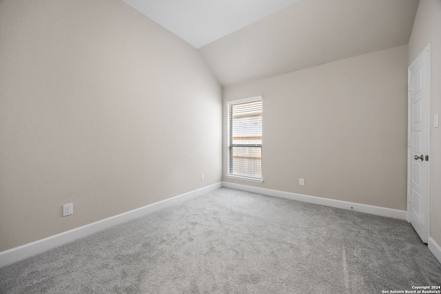 spare room featuring vaulted ceiling and carpet