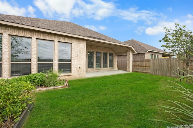 rear view of house with a patio and a lawn