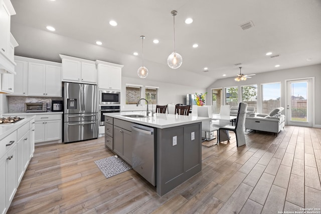 kitchen with a center island with sink, stainless steel appliances, ceiling fan, white cabinets, and sink