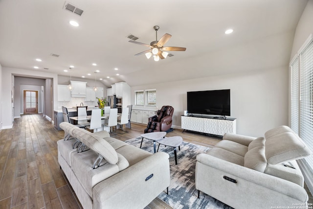 living room featuring vaulted ceiling, ceiling fan, dark hardwood / wood-style flooring, and plenty of natural light