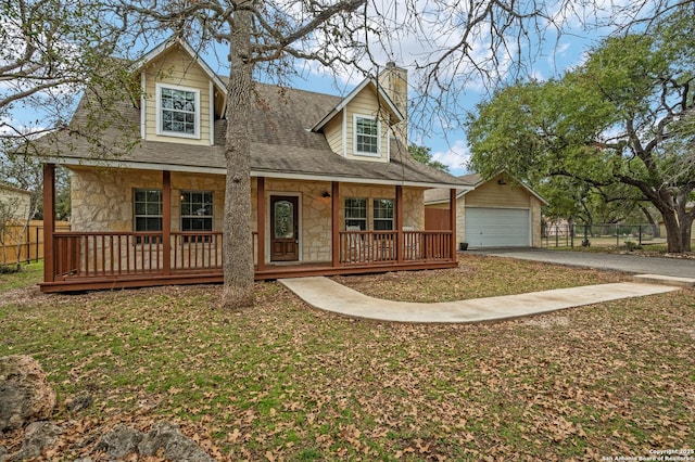 view of front of home featuring a front yard, a garage, a porch, and an outdoor structure