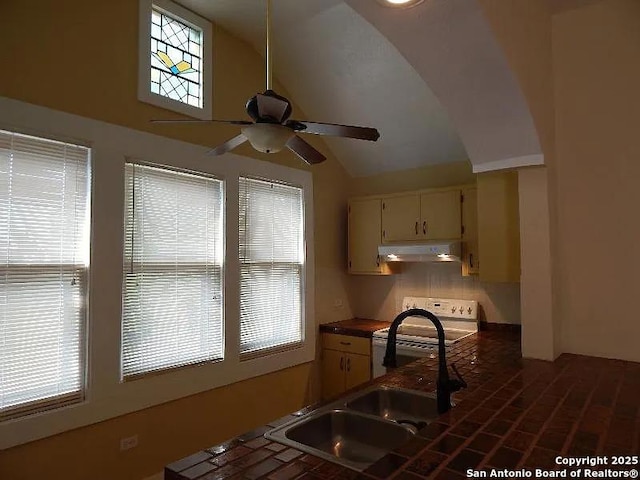 kitchen featuring ceiling fan, stove, lofted ceiling, cream cabinets, and sink