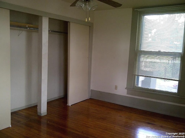 unfurnished bedroom featuring ceiling fan, dark hardwood / wood-style flooring, and multiple closets