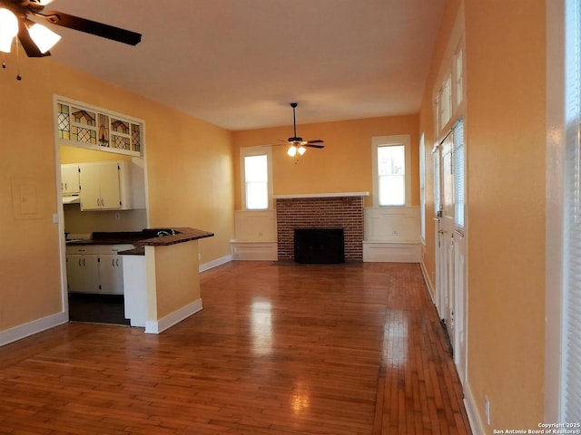 unfurnished living room with ceiling fan, a fireplace, and hardwood / wood-style floors