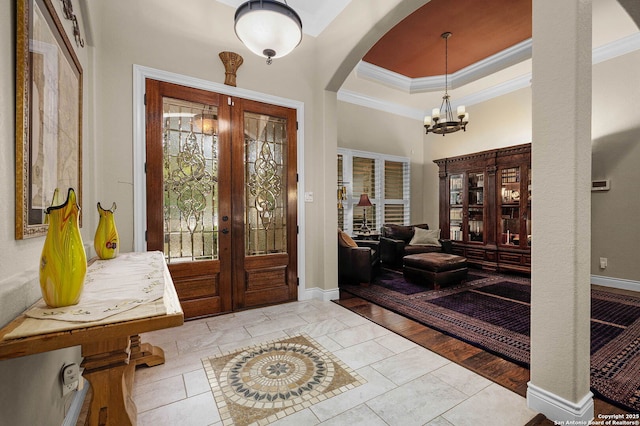 tiled entryway with french doors, an inviting chandelier, crown molding, and a tray ceiling