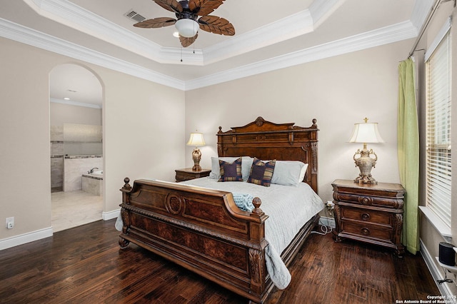 bedroom with a raised ceiling, ceiling fan, crown molding, and connected bathroom