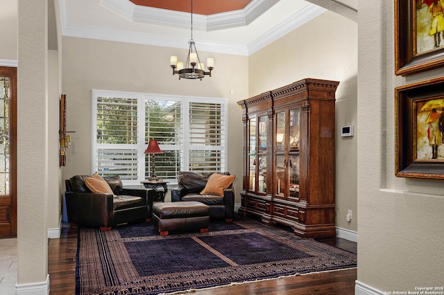 sitting room featuring ornamental molding, an inviting chandelier, hardwood / wood-style flooring, and a tray ceiling