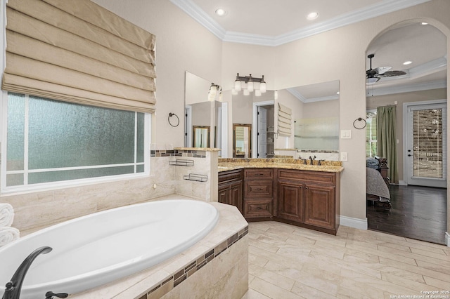 bathroom featuring ceiling fan, tiled tub, crown molding, and vanity