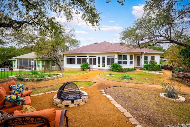 back of house featuring a fire pit, a yard, and a sunroom