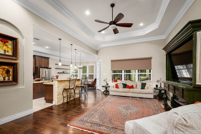 living room featuring ceiling fan with notable chandelier, a tray ceiling, crown molding, and dark hardwood / wood-style flooring