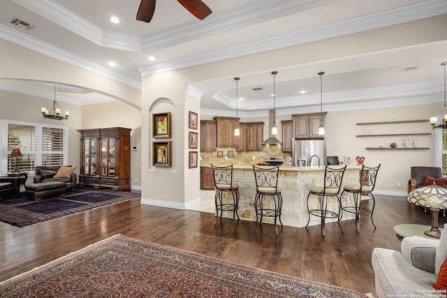 kitchen featuring decorative light fixtures, a raised ceiling, appliances with stainless steel finishes, and a breakfast bar area