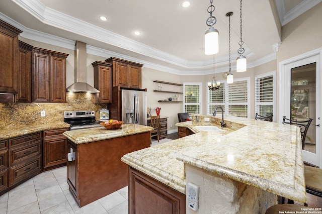 kitchen with sink, an island with sink, wall chimney range hood, a notable chandelier, and appliances with stainless steel finishes