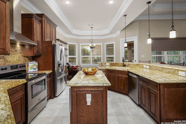 kitchen with sink, hanging light fixtures, a kitchen island, wall chimney range hood, and appliances with stainless steel finishes