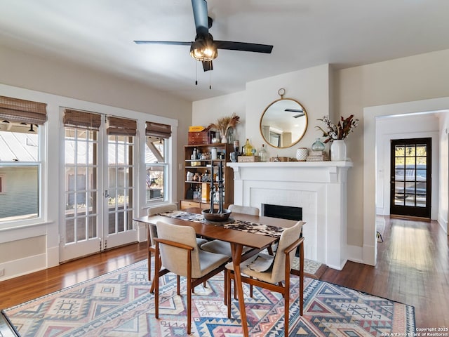 dining room with ceiling fan, a fireplace, and dark hardwood / wood-style floors