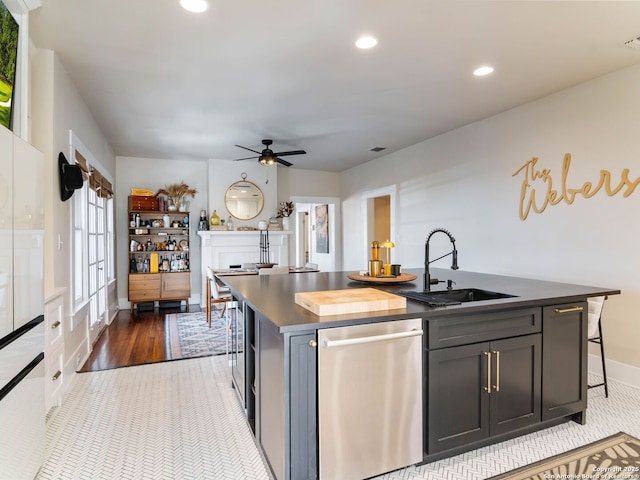 kitchen featuring a kitchen bar, sink, dishwasher, an island with sink, and ceiling fan