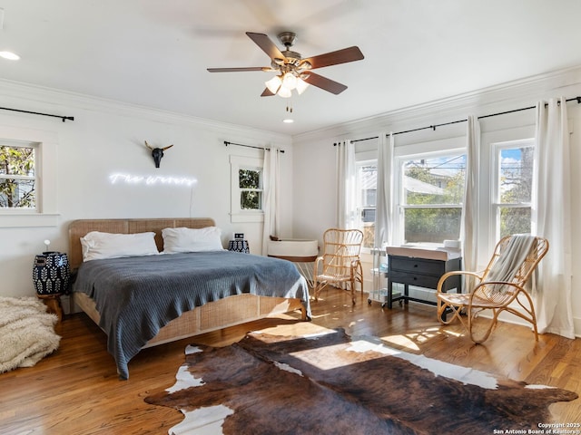 bedroom with crown molding, hardwood / wood-style flooring, and ceiling fan