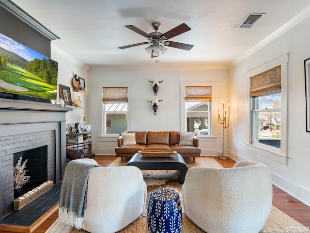 living room featuring crown molding, a brick fireplace, and a healthy amount of sunlight