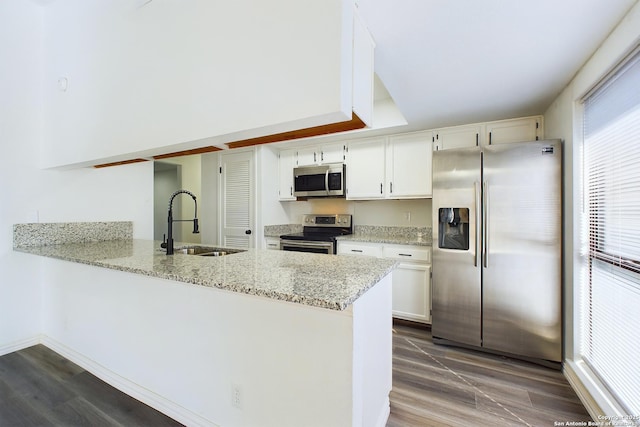 kitchen featuring sink, white cabinets, kitchen peninsula, light stone countertops, and appliances with stainless steel finishes