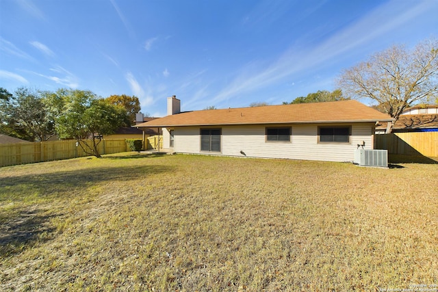 rear view of property featuring central AC and a lawn