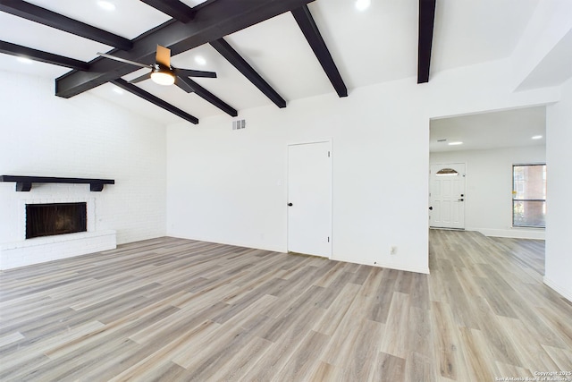 unfurnished living room featuring a brick fireplace, light wood-type flooring, ceiling fan, and lofted ceiling with beams