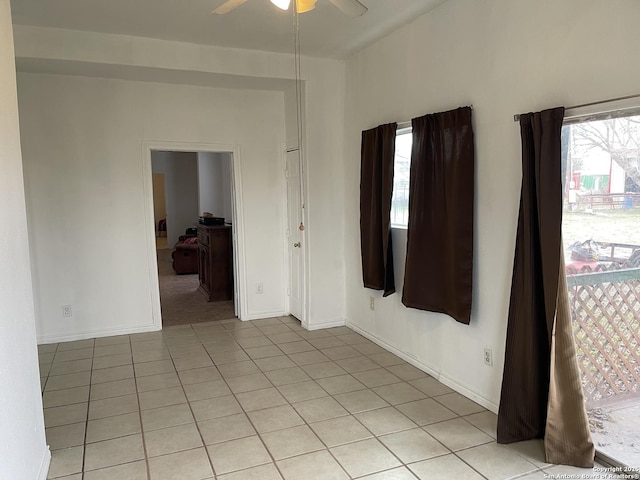 tiled spare room featuring ceiling fan and a healthy amount of sunlight