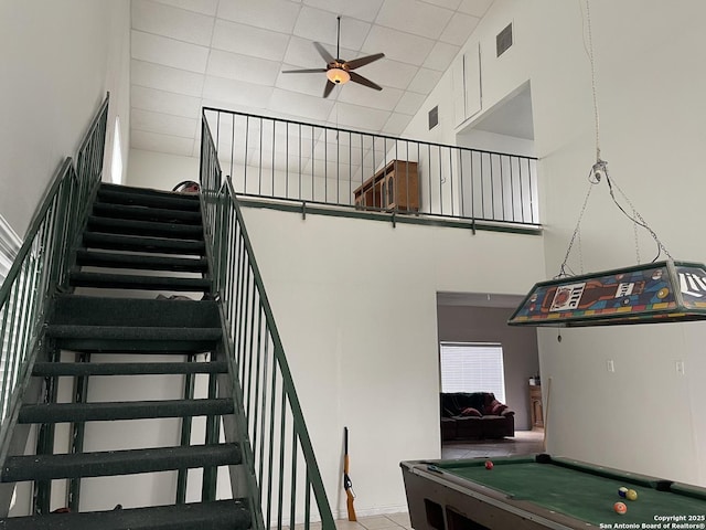 stairs with ceiling fan, a towering ceiling, and pool table