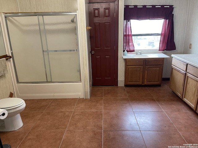 full bathroom with enclosed tub / shower combo, tile patterned floors, vanity, and toilet