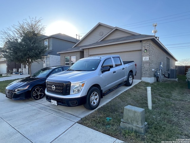 view of front of property featuring a front yard, a garage, and central AC unit