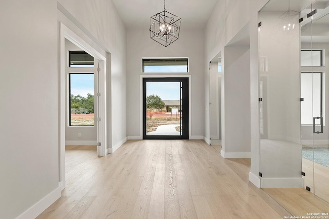 foyer with a high ceiling, a chandelier, and light hardwood / wood-style flooring