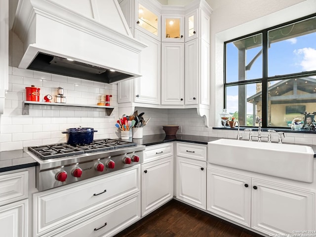 kitchen with custom exhaust hood, stainless steel gas stovetop, backsplash, white cabinetry, and sink