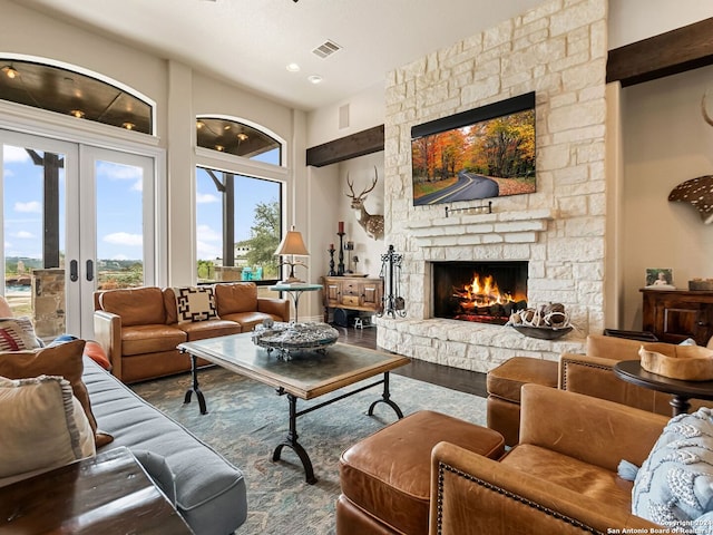 living room with french doors, a stone fireplace, and wood-type flooring