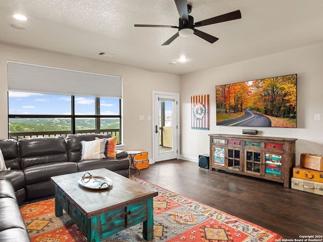 living room with ceiling fan, dark wood-type flooring, and a textured ceiling