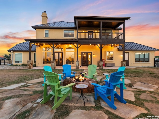 back house at dusk featuring a fire pit and a patio