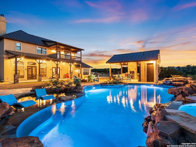 pool at dusk with french doors, an outdoor structure, and a patio area