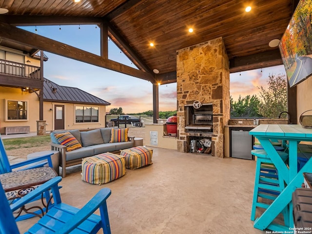 view of patio featuring a balcony, an outdoor living space with a fireplace, exterior kitchen, and grilling area