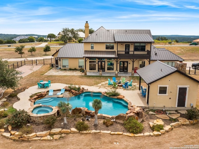 back of house featuring a pool with hot tub, a balcony, a patio, and a mountain view