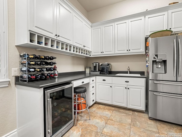 kitchen featuring sink, beverage cooler, stainless steel fridge, and white cabinetry