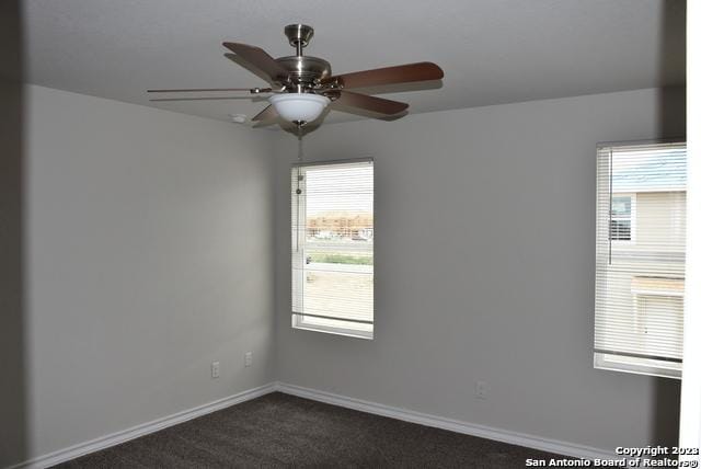 spare room with dark colored carpet and ceiling fan