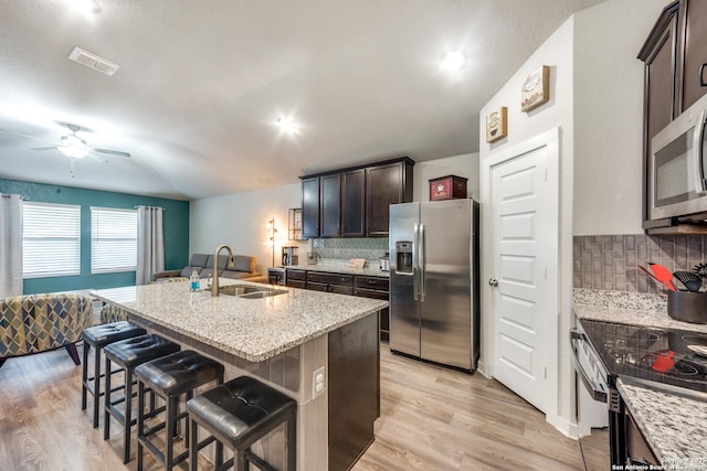 kitchen featuring sink, stainless steel appliances, a kitchen island with sink, and decorative backsplash