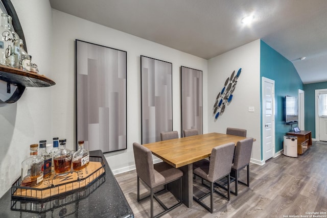 dining area featuring vaulted ceiling and wood-type flooring