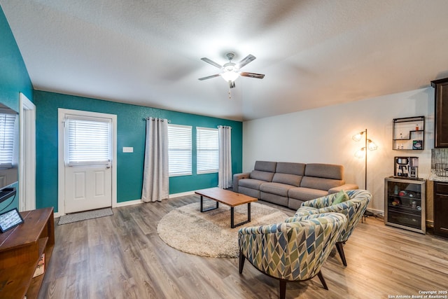 living room with a textured ceiling, ceiling fan, light wood-type flooring, and beverage cooler