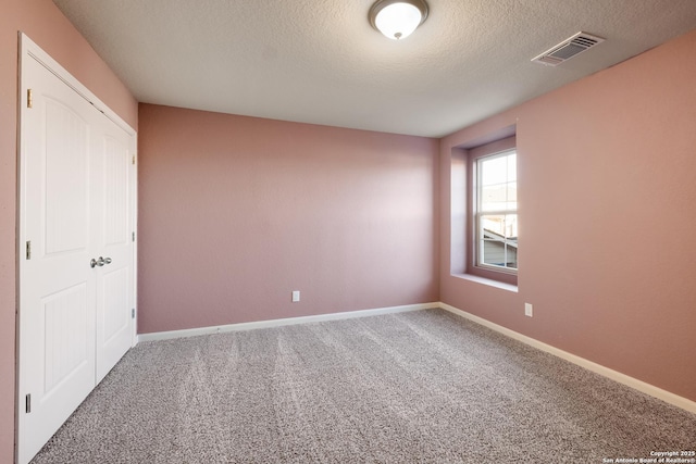 spare room with a textured ceiling and carpet floors