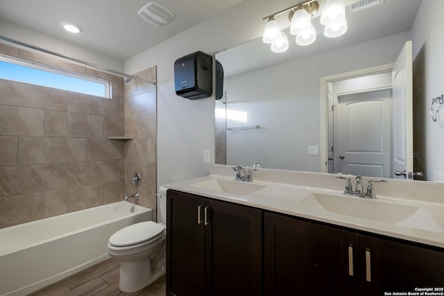 full bathroom featuring toilet, wood-type flooring, vanity, and tiled shower / bath