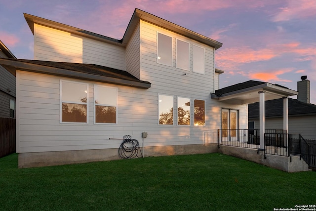 back house at dusk with a lawn