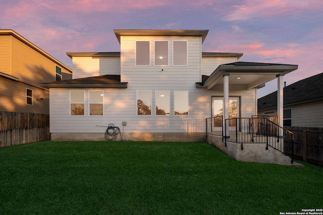 back house at dusk featuring a yard