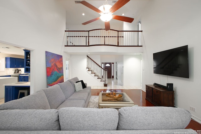 living room featuring a high ceiling, dark hardwood / wood-style flooring, and ceiling fan