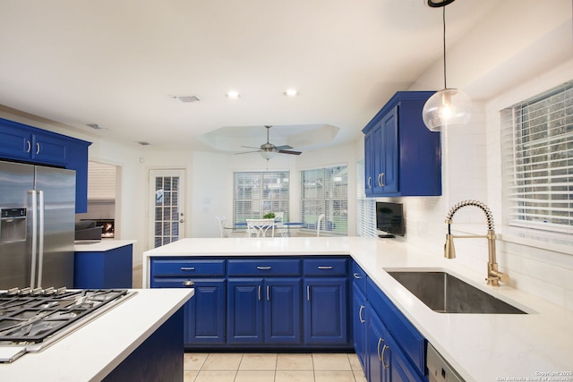 kitchen with stainless steel appliances, ceiling fan, sink, decorative light fixtures, and blue cabinets